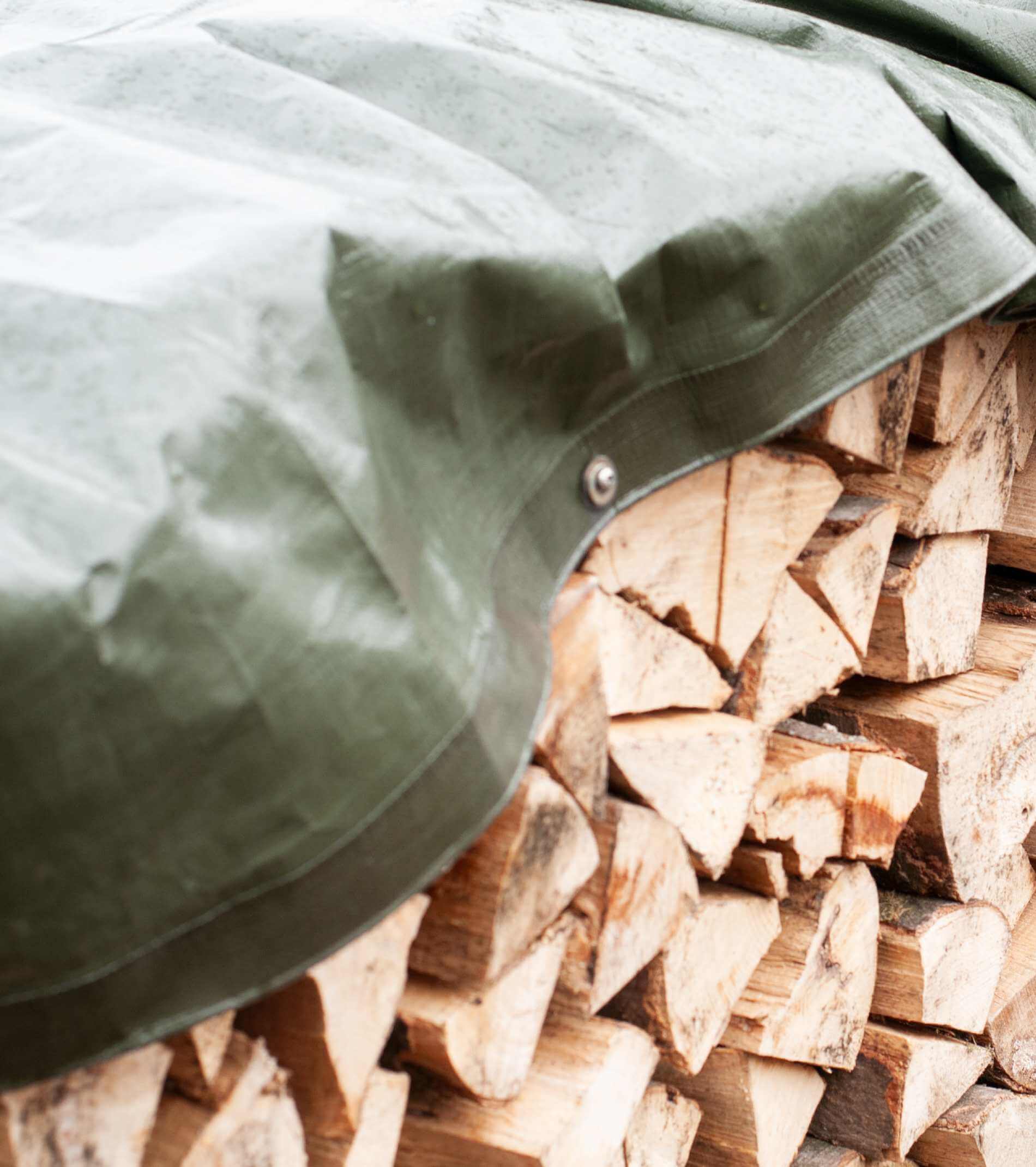 firewood covered with a waterproof green tarpaulin